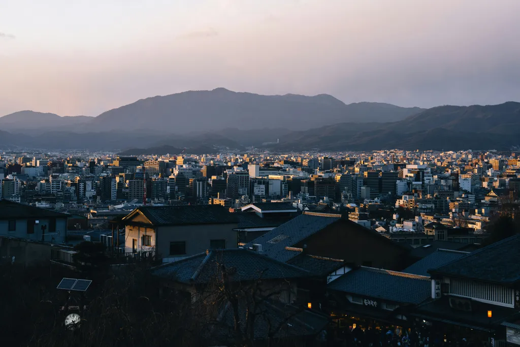 Cityscape at dusk, with mountains in background.